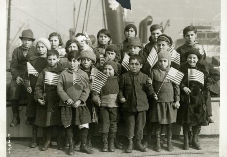 Black and white photo. 20 children showing a various of emotions from smiles, to somber, to sad.