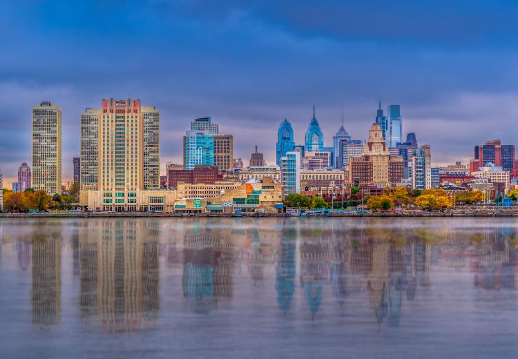 Panoramic photo of the Philadelphia skyline during the daytime with reflection coming off of the Delaware River